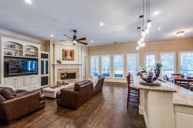 2458 W Creek Dr, Frisco, TX 75033 - living room featuring a ceiling fan, ornamental molding, dark wood finished floors, a stone fireplace, and plenty of natural light