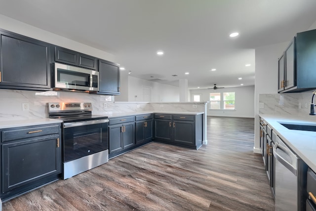 1722 Harvest Crossing Dr, Wylie, TX 75098 - kitchen featuring stainless steel appliances, a peninsula, dark wood-style flooring, a sink, and recessed lighting
