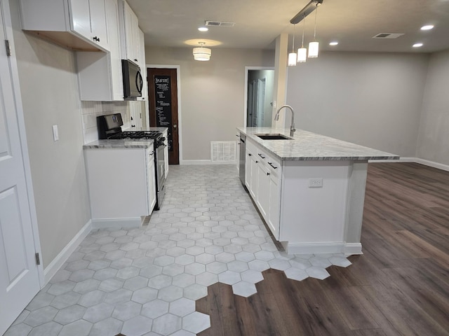 220 Bluebird Cir, Denton, TX 76209 - kitchen featuring stainless steel appliances, a sink, baseboards, white cabinetry, and light stone countertops