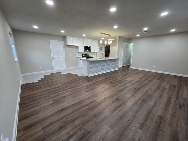220 Bluebird Cir, Denton, TX 76209 - unfurnished living room with dark wood-style flooring, baseboards, recessed lighting, and a sink