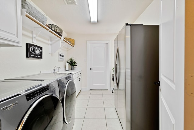 7100 King Ranch Rd, North Richland Hills, TX 76182 - laundry area featuring washing machine and dryer, cabinet space, light tile patterned flooring, and baseboards