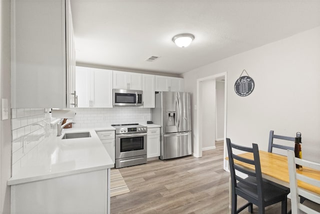 1503 Dale Dr, Arlington, TX 76010 - kitchen with stainless steel appliances, a sink, tasteful backsplash, light countertops, and light wood-style flooring
