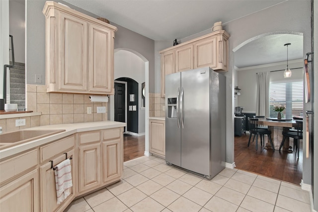 103 Daisey Ln, Justin, TX 76247 - kitchen with stainless steel refrigerator with ice dispenser, arched walkways, light brown cabinets, tasteful backsplash, and ornamental molding