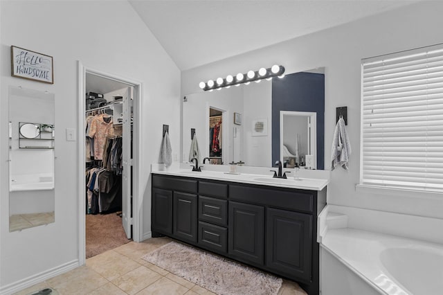 103 Daisey Ln, Justin, TX 76247 - bathroom featuring lofted ceiling, double vanity, a spacious closet, a bath, and tile patterned flooring