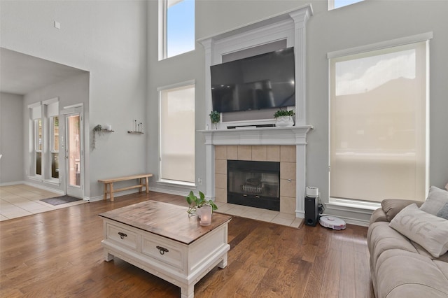 103 Daisey Ln, Justin, TX 76247 - living area featuring wood finished floors, a high ceiling, a tile fireplace, and baseboards