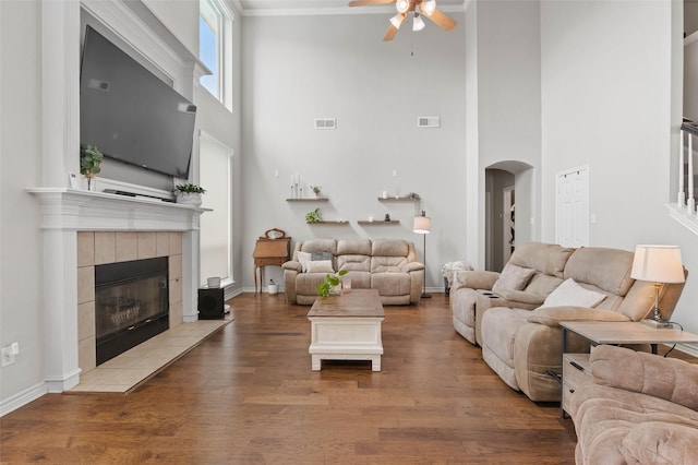 103 Daisey Ln, Justin, TX 76247 - living area featuring ceiling fan, arched walkways, a tiled fireplace, wood finished floors, and a towering ceiling