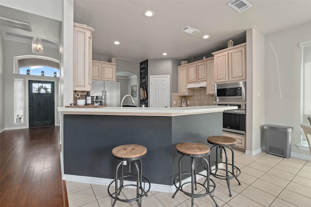 103 Daisey Ln, Justin, TX 76247 - kitchen featuring appliances with stainless steel finishes, a kitchen breakfast bar, a sink, backsplash, and light brown cabinets