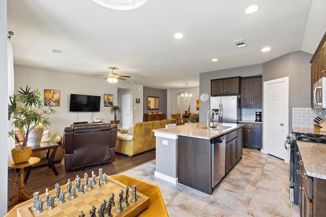 616 Forefront Ave, Celina, TX 75009 - kitchen with appliances with stainless steel finishes, a ceiling fan, dark brown cabinets, a sink, and a kitchen island with sink