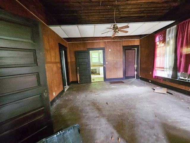 823 W Louisiana St, Palestine, TX 75801 - unfurnished living room featuring wood walls, baseboards, ceiling fan, and concrete flooring