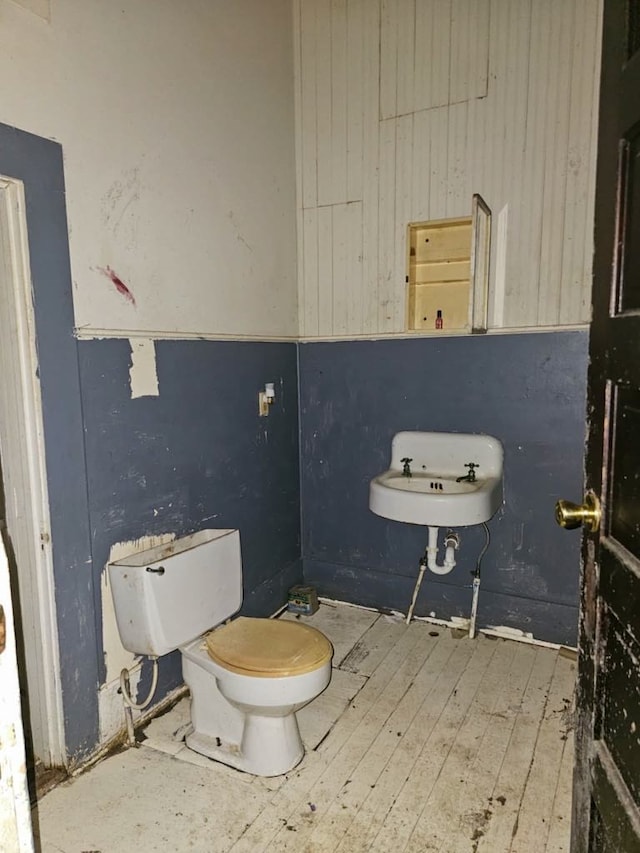 823 W Louisiana St, Palestine, TX 75801 - bathroom with toilet, hardwood / wood-style flooring, wooden walls, and a sink