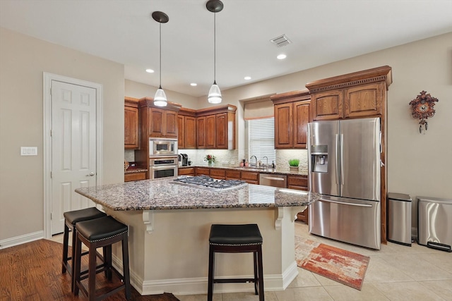 9352 Blanco Dr, Lantana, TX 76226 - kitchen featuring appliances with stainless steel finishes, light stone countertops, a sink, a kitchen bar, and a kitchen island