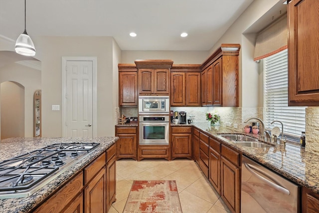 9352 Blanco Dr, Lantana, TX 76226 - kitchen featuring appliances with stainless steel finishes, arched walkways, a sink, stone countertops, and backsplash
