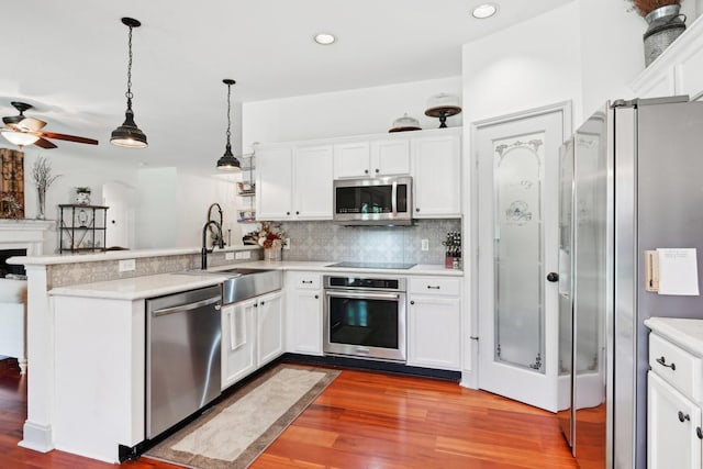 921 Stoneway Dr, Denton, TX 76210 - kitchen featuring stainless steel appliances, a sink, a peninsula, wood finished floors, and white cabinetry