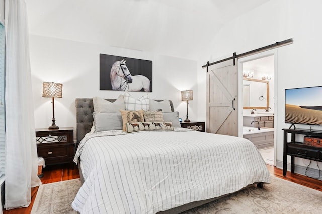 921 Stoneway Dr, Denton, TX 76210 - bedroom with a barn door, wood finished floors, vaulted ceiling, and ensuite bath