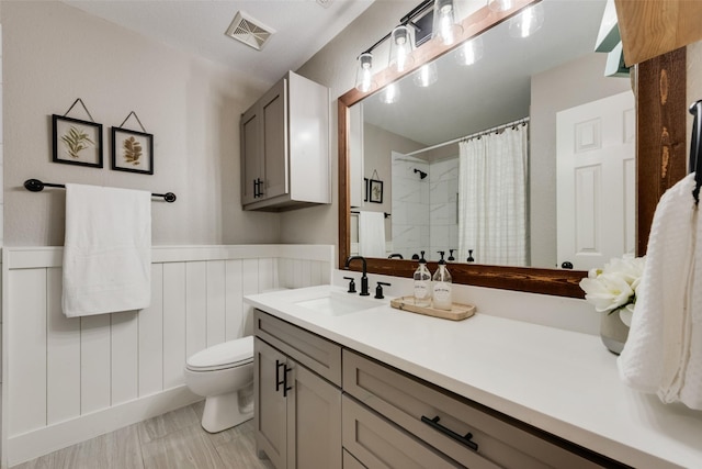 5536 Green Hollow Ln, The Colony, TX 75056 - bathroom with toilet, vanity, curtained shower, and a wainscoted wall