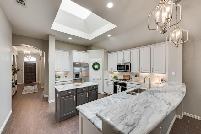 5536 Green Hollow Ln, The Colony, TX 75056 - kitchen with stainless steel appliances, a sink, arched walkways, baseboards, and white cabinetry