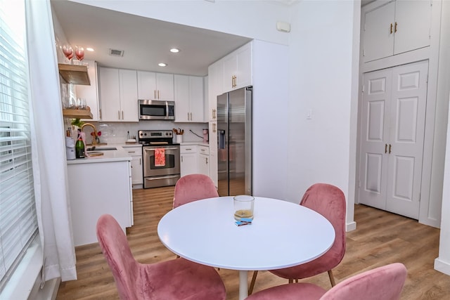 3311 Blackburn St Unit 115, Dallas, TX 75204 - kitchen featuring appliances with stainless steel finishes, a sink, white cabinets, light countertops, and light wood-style flooring