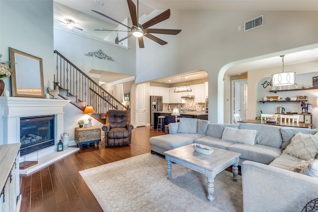 1386 Caspian Dr, Roanoke, TX 76262 - living area featuring ceiling fan, arched walkways, dark wood-type flooring, high vaulted ceiling, and stairway