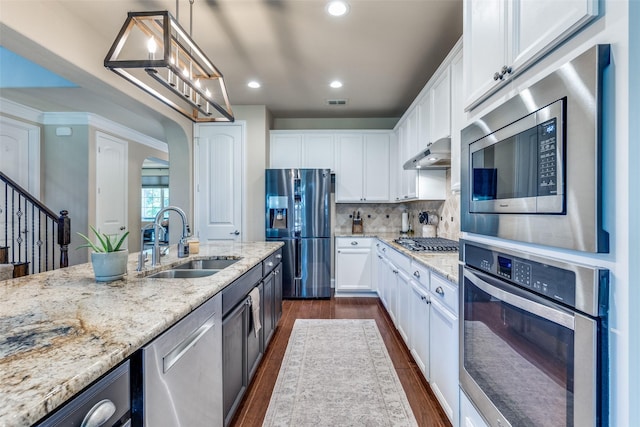 1386 Caspian Dr, Roanoke, TX 76262 - kitchen with stainless steel appliances, a sink, under cabinet range hood, light stone countertops, and dark wood-type flooring