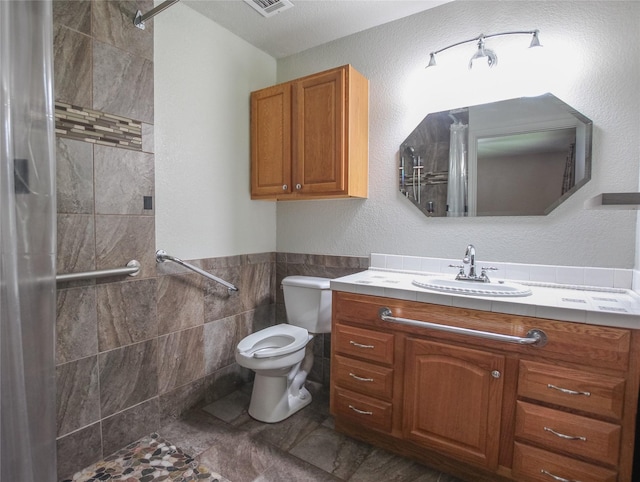 107 Clover Dr, Gun Barrel City, TX 75156 - full bathroom featuring tile walls, toilet, vanity, tiled shower, and wainscoting