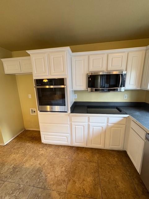 5421 Palace Dr, Richardson, TX 75082 - kitchen with stainless steel appliances, dark countertops, white cabinetry, and dark tile patterned flooring