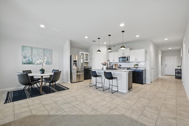 3800 Canyon Verde Ln, Denton, TX 76226 - kitchen with appliances with stainless steel finishes, a kitchen island with sink, decorative backsplash, a kitchen breakfast bar, and white cabinetry