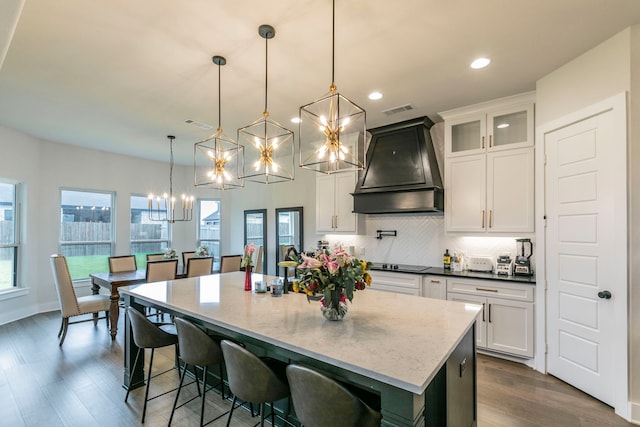 2104 Palafox Dr, Waco, TX 76655 - kitchen featuring custom range hood, a chandelier, decorative backsplash, a center island with sink, and white cabinets