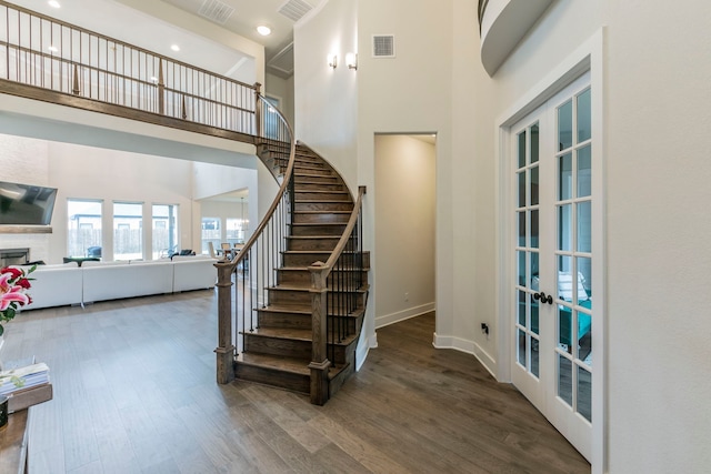 2104 Palafox Dr, Waco, TX 76655 - staircase featuring french doors, a towering ceiling, wood finished floors, a fireplace, and baseboards