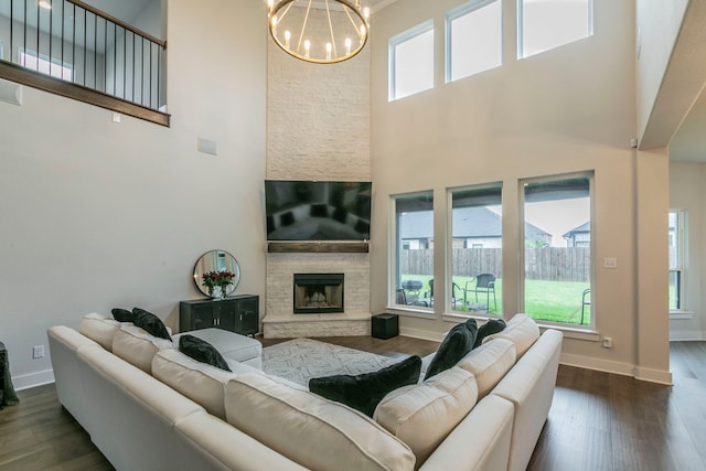 2104 Palafox Dr, Waco, TX 76655 - living area with a towering ceiling, a chandelier, dark wood-style flooring, a stone fireplace, and baseboards