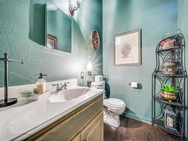 306 E Tarrant St, Bowie, TX 76230 - bathroom with a textured wall, wood finished floors, toilet, vanity, and baseboards