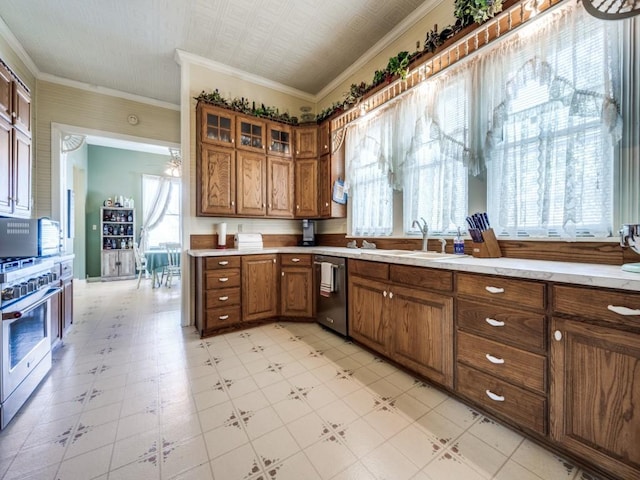306 E Tarrant St, Bowie, TX 76230 - kitchen with a sink, appliances with stainless steel finishes, brown cabinetry, light countertops, and ornamental molding
