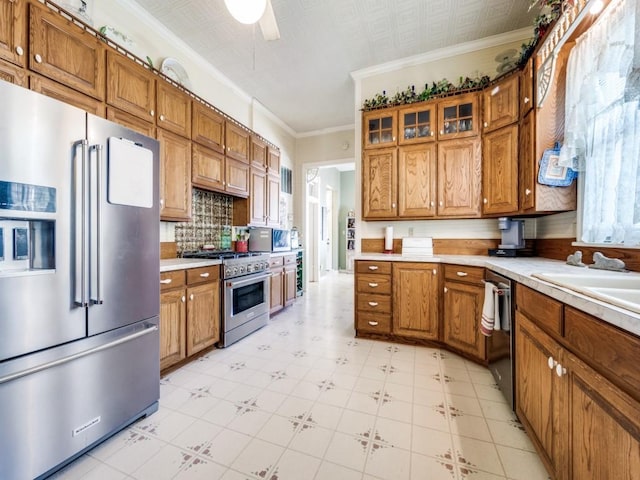 306 E Tarrant St, Bowie, TX 76230 - kitchen with premium appliances, light countertops, brown cabinetry, crown molding, and light flooring