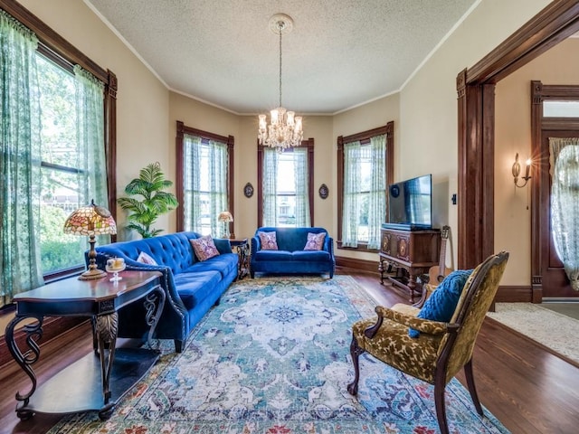 306 E Tarrant St, Bowie, TX 76230 - living room with a chandelier, wood finished floors, a textured ceiling, ornamental molding, and baseboards