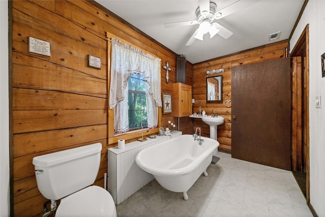 225 Springwood Cir, Chandler, TX 75758 - full bathroom featuring wooden walls, a freestanding tub, toilet, ceiling fan, and rustic walls
