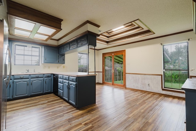 1103 Bluebonnet Hill Dr, Ennis, TX 75119 - kitchen featuring crown molding, a peninsula, light wood-style flooring, blue cabinetry, and light countertops