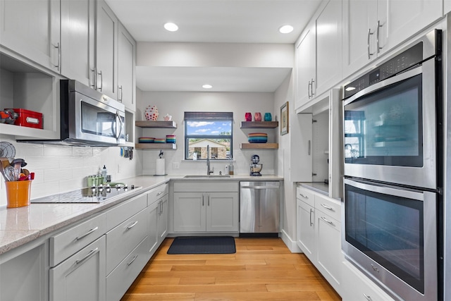 5120 Fairway Cir, Granbury, TX 76049 - kitchen with open shelves, stainless steel appliances, a sink, light wood-style floors, and decorative backsplash