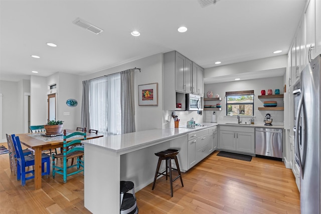 5120 Fairway Cir, Granbury, TX 76049 - kitchen featuring appliances with stainless steel finishes, open shelves, a peninsula, a sink, and light wood finished floors