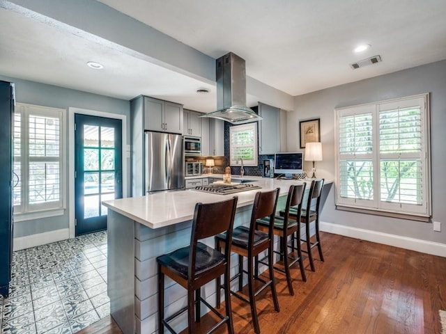 879 Peavy Rd, Dallas, TX 75218 - kitchen featuring appliances with stainless steel finishes, island exhaust hood, gray cabinetry, baseboards, and light countertops