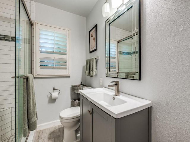879 Peavy Rd, Dallas, TX 75218 - full bathroom with vanity, a shower stall, toilet, wood finished floors, and baseboards