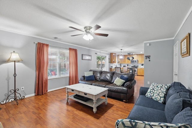 1500 Caymus Ct, Lewisville, TX 75067 - living room featuring ceiling fan, light wood finished floors, crown molding, a textured ceiling, and baseboards