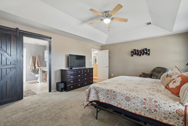 1500 Caymus Ct, Lewisville, TX 75067 - carpeted bedroom with a raised ceiling, a barn door, baseboards, a ceiling fan, and connected bathroom