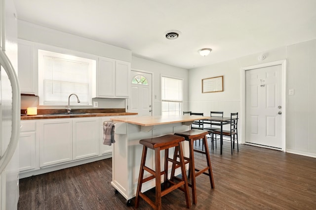 3249 Sandefer St, Abilene, TX 79603 - kitchen with a sink, dark wood finished floors, a breakfast bar area, white cabinetry, and freestanding refrigerator