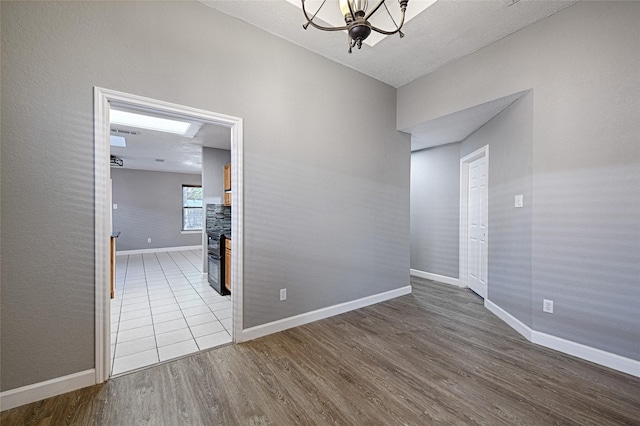 3019 Lela St, Irving, TX 75061 - spare room featuring wood finished floors, a chandelier, a stone fireplace, and a textured ceiling