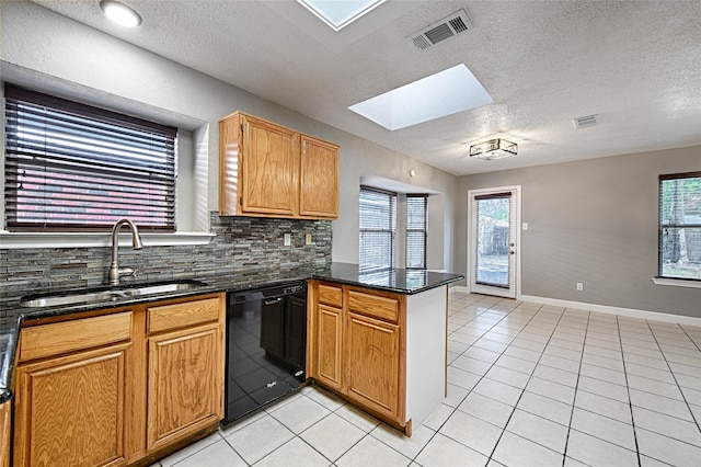 3019 Lela St, Irving, TX 75061 - kitchen with black dishwasher, a skylight, a peninsula, light tile patterned flooring, and a textured ceiling