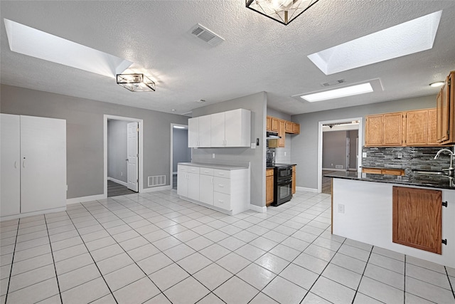 3019 Lela St, Irving, TX 75061 - kitchen featuring black range, backsplash, a textured ceiling, exhaust hood, and light tile patterned floors