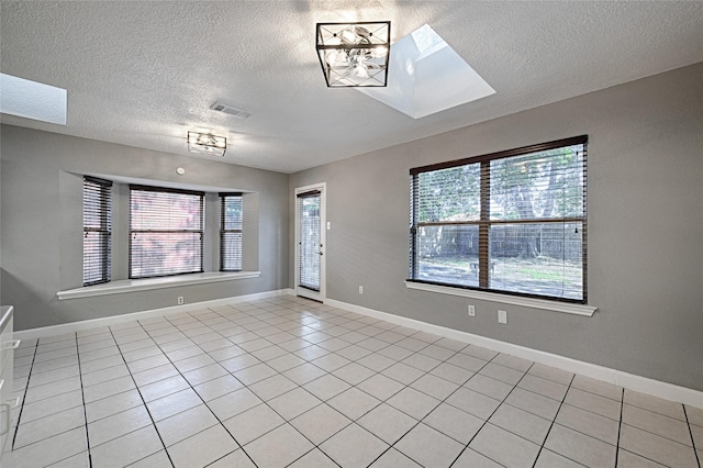 3019 Lela St, Irving, TX 75061 - empty room with a skylight, a textured ceiling, and light tile patterned flooring
