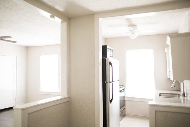 4107 Herschel Ave, Dallas, TX 75219 - kitchen with a sink, freestanding refrigerator, a ceiling fan, range, and light countertops