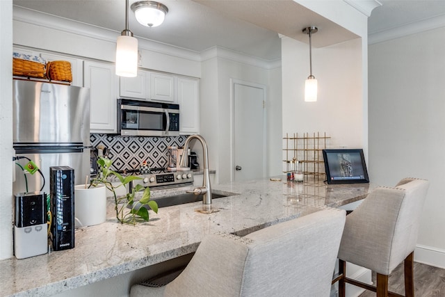 5927 E University Blvd Unit 217, Dallas, TX 75206 - kitchen featuring stainless steel microwave, tasteful backsplash, ornamental molding, light stone countertops, and white cabinetry