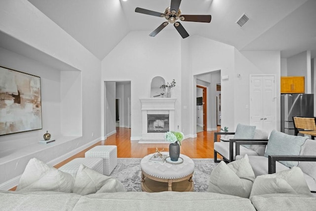 2425 Sir Lovel Ln, Lewisville, TX 75056 - living area featuring light wood finished floors, a ceiling fan, baseboards, a glass covered fireplace, and high vaulted ceiling
