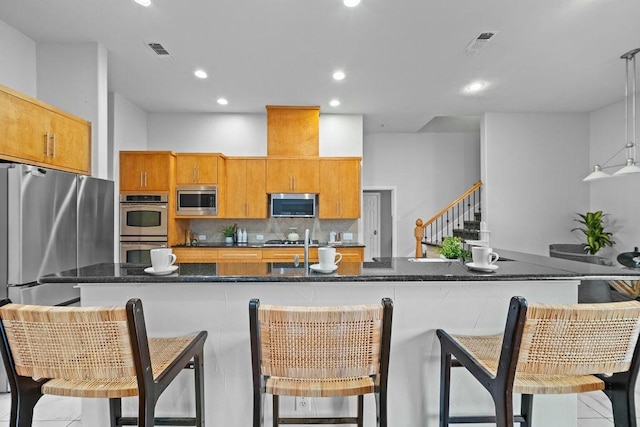 2425 Sir Lovel Ln, Lewisville, TX 75056 - kitchen with appliances with stainless steel finishes, brown cabinetry, tasteful backsplash, recessed lighting, and a kitchen breakfast bar